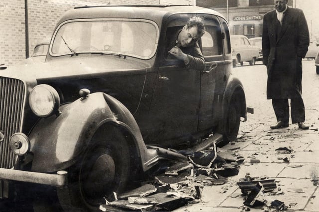 Ronald Bullimore looks at his damaged car which was struck by a falling chimney stack during the hurricane on February 16, 1962