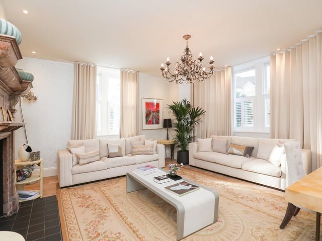 The formal lounge features a large stone fireplace, high ceilings, intricate architraves and large sash windows, flooding the room with natural light.