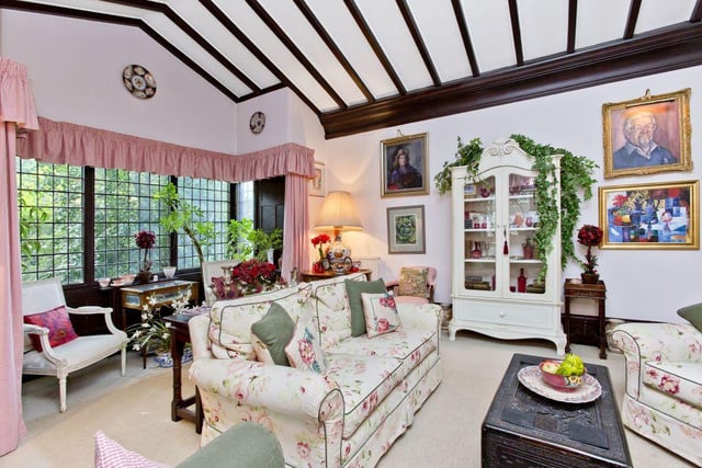The impressive drawing room has a vaulted ceiling with exposed beams and large glass box bay windows.