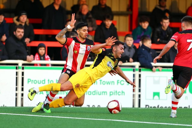 Ilkeston Town's Aman Verma brings down Belper Town's Jonathon Margetts in the area to concede a penalty.