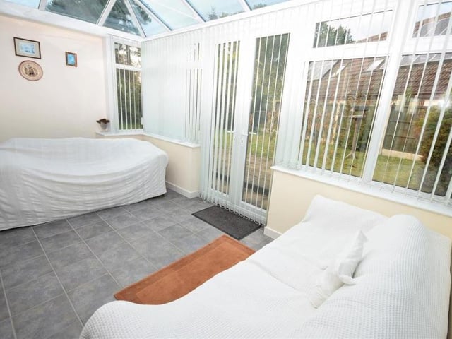 Although the seats are covered, this photo gives a good idea of how bright and airy the conservatory is. It is a versatile space with practical, tiled flooring and doors opening out to the back garden.