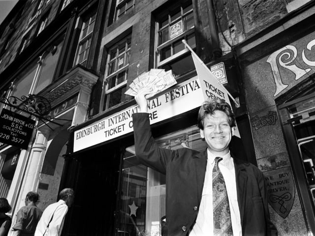British actor Kenneth Branagh holds up some leaflets outside the Edinburgh Festival's new box office by St Giles Cathedral in the Royal Mile, August 1990.