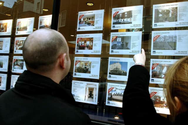 A young couple studying property for sale in an estate agent's window as the stamp duty holiday runs out