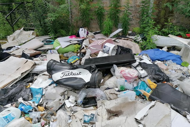 Rubbish, including carpopets, a golf bag, clothes and debris dumped outside the listed building