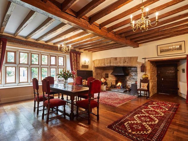 The formal dining area still features the original oak ceiling beams, a huge open stone fireplace, and original wooden floors.
