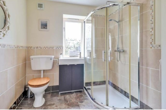 This the pleasant en suite shower room to the ground-floor bedroom. As well as the shower cubicle, it features a wash hand basin and low-flush WC.