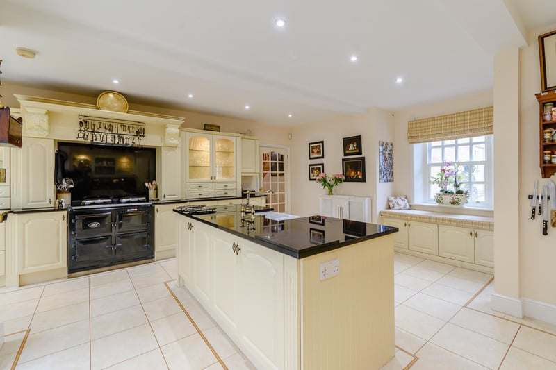 A large central island with a double Belfast sink, an Aga and modern integrated appliances.