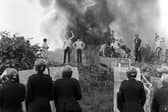 File photo dated 18 June 1984, of anti-riot squad police watching as pickets face them against a background of burning cars at the Orgreave coke works. Photo: PA