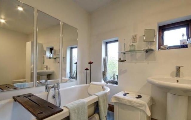 This particular bathroom has s freestanding bath with mixer shower, shower cubicle with mains fed shower, pedestal hand basin, wc, and heated towel rail.