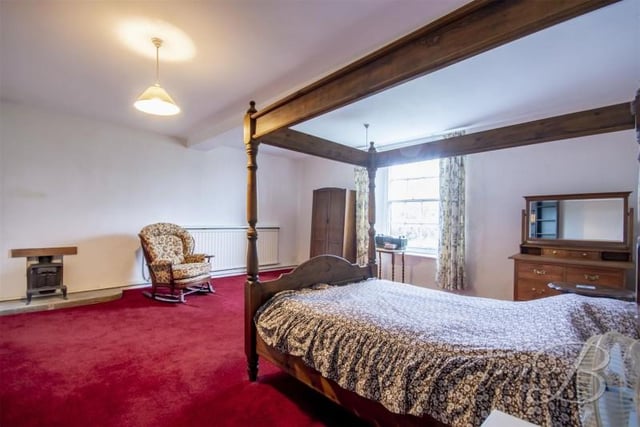 This bedroom has a tiny fireplace a plenty of space for a four poster bed.