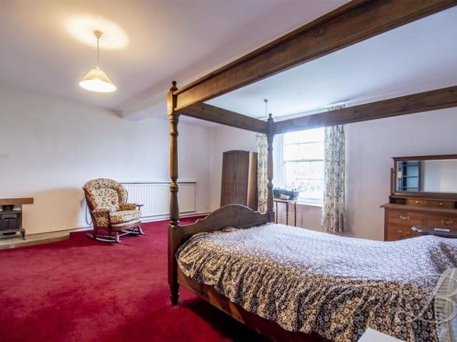 This bedroom has a tiny fireplace a plenty of space for a four poster bed.