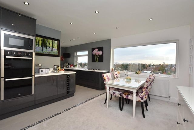 Double doors lead into the modern open plan kitchen diner, which is fitted with a range of high gloss grey units and integrated appliances, including a microwave and dishwasher.