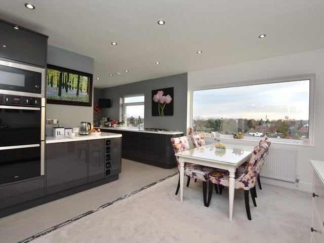 Double doors lead into the modern open plan kitchen diner, which is fitted with a range of high gloss grey units and integrated appliances, including a microwave and dishwasher.