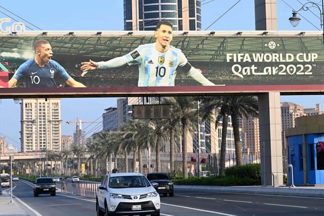Motorists drive past a billboard with pictures of France's striker Kylian Mbappe (L) and Argentine's captain Lionel Messi in Doha, Qatar, ahead of the World Cup: GABRIEL BOUYS/AFP via Getty Images
