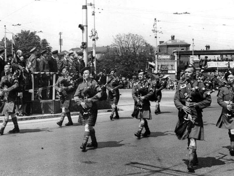 Bagpipes through Guildhall Square Wings for Victory week
On May 28, 1943, the Secretary of State for Foreign Affairs Rt. Hon. Anthony Eden K.C. MP visited the city.
It was Wings for Victory week and a large parade of servicemen and women plus the police paraded through the square.
Eden can be seen on the platform at the rear, in the suit.