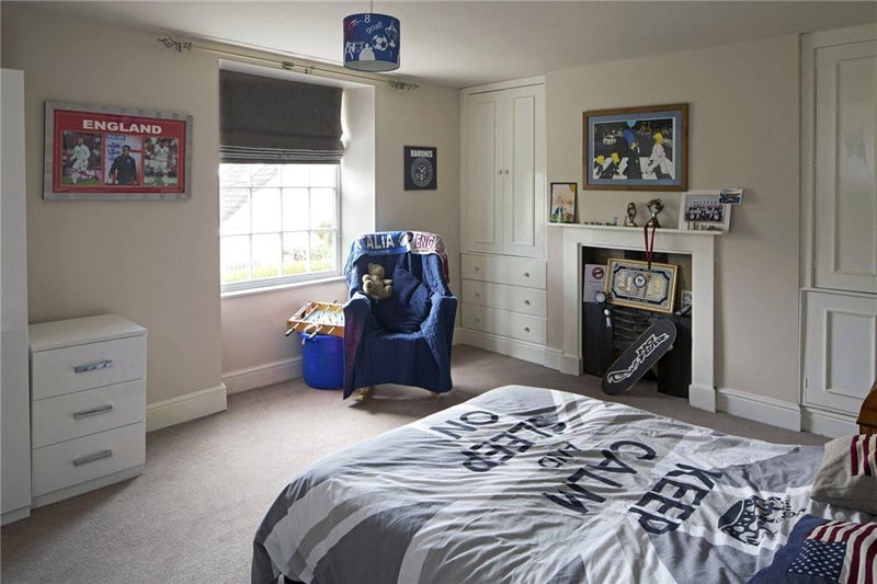 This bedroom has a painted fire surround with inset decorative dog grate, and cupboards to either side of the chimney breast with drawers beneath.