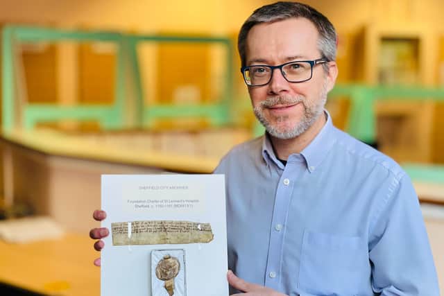 Archivist Pete Evans holding the archives oldest document, dating back to 1150, at the Shoreham Street building