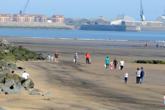 Families can be seen keeping their distance from each other as they walk along the beach at Seaton Carew.