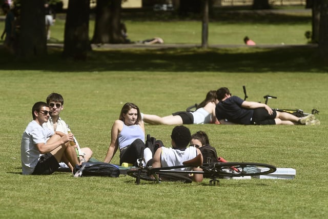 A group of friends sit in the sunshine at The Meadows.