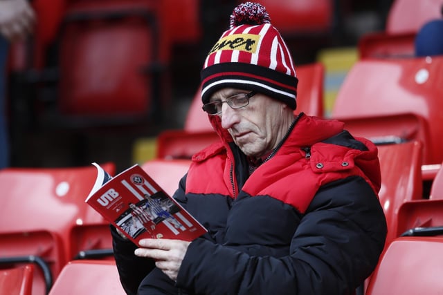 A United supporter reads the matchday programme before the game with Brighton & Hove Albion last February.