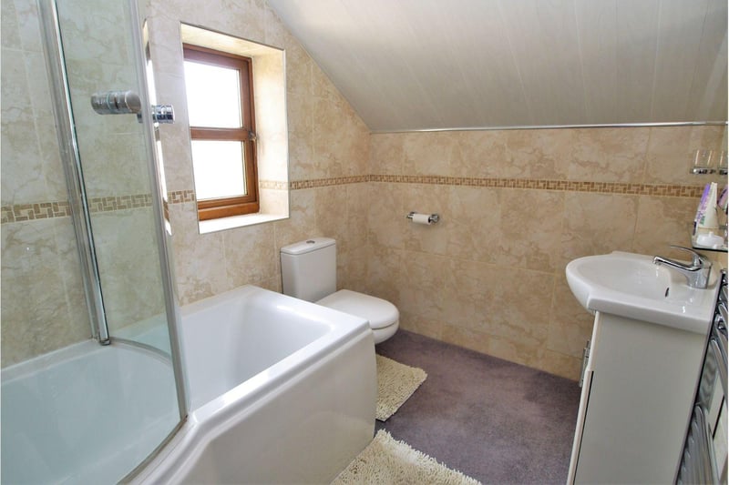 Having a suite comprising panelled shower bath, low-level WC and vanity unit with mounted wash basin.