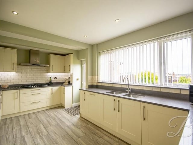 Having a sink and drainer unit set into ample working surfaces benefiting from complementary tiled splashbacks. With laminate flooring and a door providing access outside for convenience.