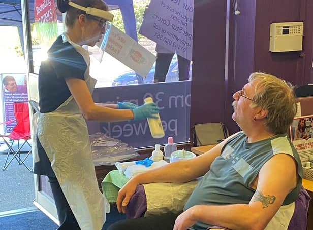 Member of staff Paul having his arms waxed to raise money by Helping Hands carer Steph