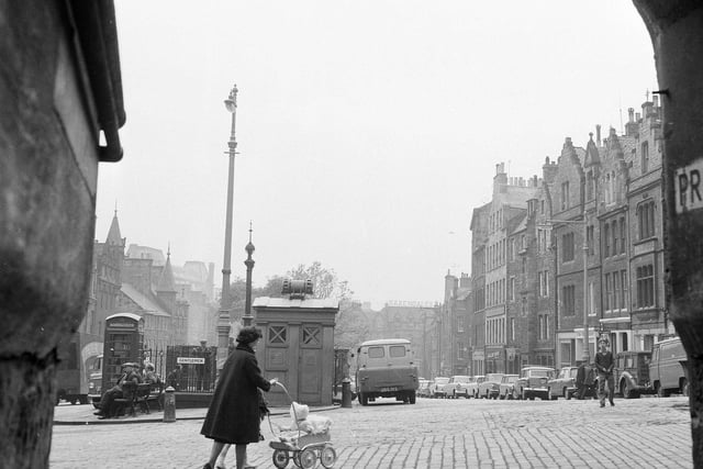 A woman is pictured pushing a pram past the police box and former gents' toilets in the Grassmarket in 1965.