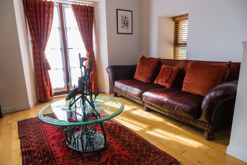 TRhe living room has a luxurious leather couch, plus a high-tech television and sound system.