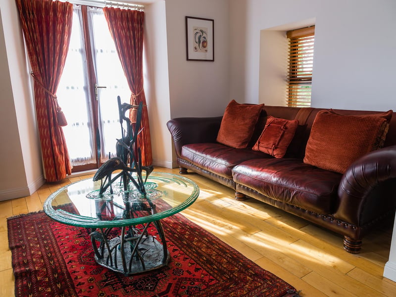 TRhe living room has a luxurious leather couch, plus a high-tech television and sound system.