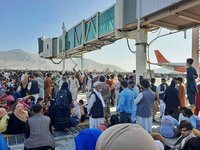 Afghans crowd at the tarmac of the Kabul airport to flee the country as the Taliban were in control of Afghanistan after President Ashraf Ghani fled the country and conceded the insurgents had won the 20-year war.