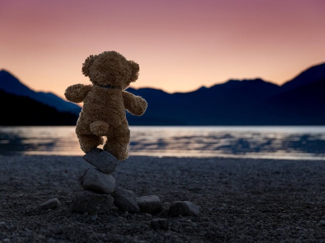 John James the teddy bear at sunset on the Bavarian lake Walchensee in Germany. See SWNS copy SWCAteddy:
These adorable teddy bears could be the world's most well-travelled cuddly toys - as their photographer owner has chronicled their adventures in 27 different countries. Christian Kneidinger, 57, has been travelling with his teddy bears, named John and Bob since 2014 - and his taken them to some of the world's most famous landmarks. The teddy bears have dressed up in traditional Emirati clothing to visit the Sultan's Palace in Oman, and have braved the cold on a glacier on Lofoten Island in Norway.