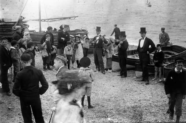 circa 1895:  A trio of musicians attract a small crowd of children on Southsea  beach.  (Photo by F J Mortimer/Hulton Archive/Getty Images)