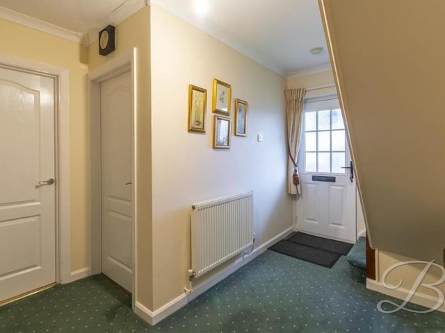 This is the entrance hallway to the bungalow. It has a carpeted floor, central-heating radiator and access to the kitchen and living room.