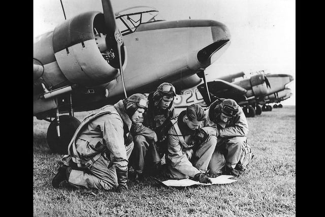 Pilots read a map in front of an Airspeed Oxford.