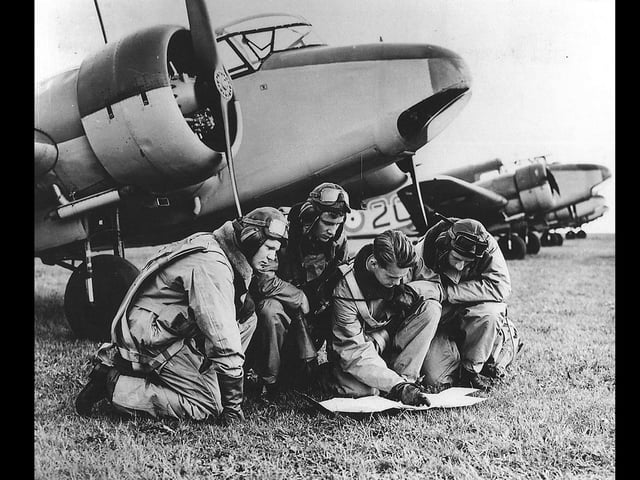 Pilots read a map in front of an Airspeed Oxford.