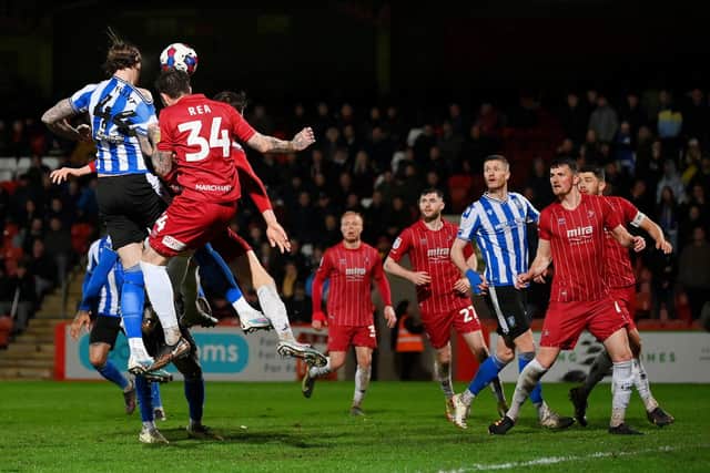 Aden Flint of Sheffield Wednesday scores the team's first goal whilst under pressure from Glen Rea of Cheltenham Town during the Sky Bet League One between Cheltenham Town and Sheffield Wednesday at Completely-Suzuki Stadium on March 29, 2023 in Cheltenham, England. (Photo by Dan Mullan/Getty Images)