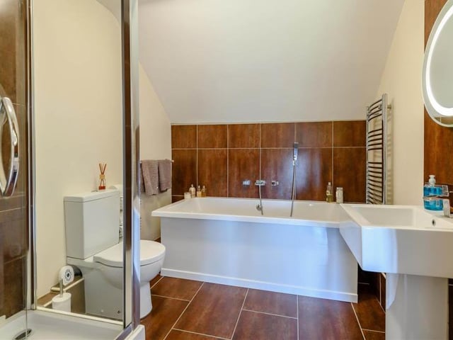 The second floor also houses a second family bathroom, complete with a modern four-piece suite. It comprises a large bath-tub, separate shower enclosure, pedestal wash hand basin with fitted mirror and LED lighting above, and a low-flush WC, not to mention a heated towel-rail.