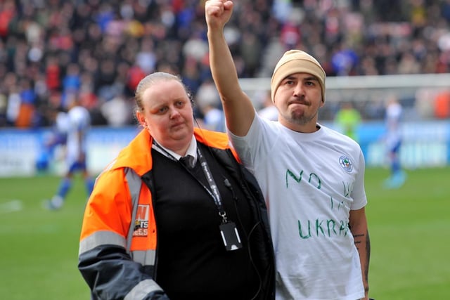 A Wigan fan is removed from the field of play after he made a statement on the pitch against Sunderland.