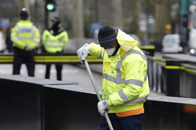 A street cleaner wearing a mask works outside the Houses of Parliament in London on March 18, 2020 amid the coronavirus outbreak (Photo by ADRIAN DENNIS/AFP via Getty Images)