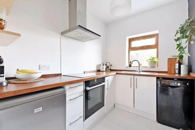 The  kitchen has a range of modern units with solid wood worktops, a glass splash-back and a painted wood floor. A rear window provides a pleasant garden outlook.