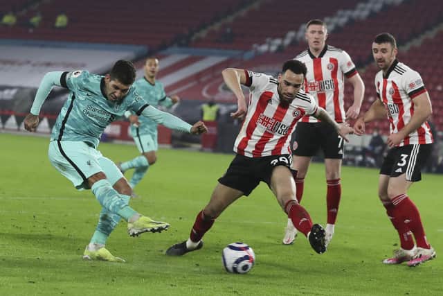 Liverpool's Roberto Firmino, left, scores his side's second goal during the English Premier League soccer match between Sheffield United and Liverpool at Bramall Lane stadium in Sheffield, England, Sunday, Feb. 28, 2021: Lee Smith, Pool via AP