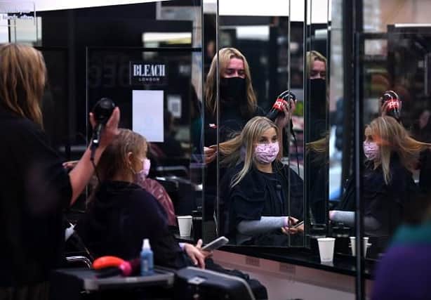 A customer has her hair dried following a haircut inside a salon. (Photo by DANIEL LEAL-OLIVAS/AFP via Getty Images)