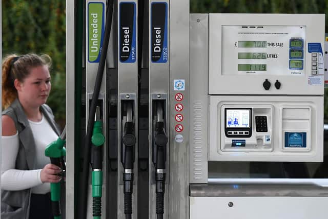 A woman replaces a fuel nozzle in a petrol pump at a petrol station. Picture: Anthony Devlin/AFP via Getty Images.