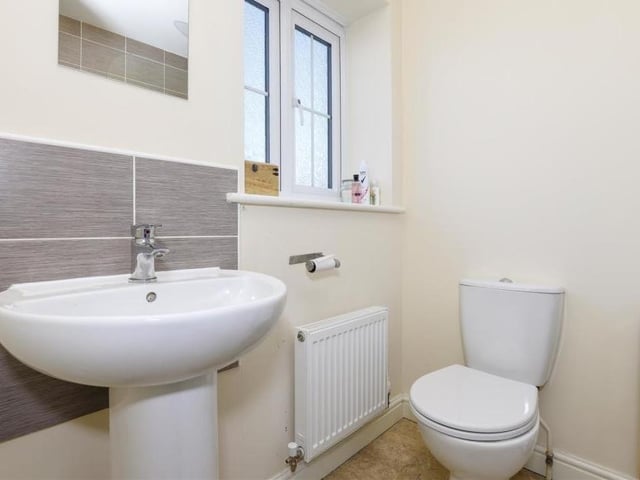 The first of two shots of the family bathroom on the first floor. It features tiled flooring, a wall-mounted radiator, low-level flush WC and a pedestal wash basin.
