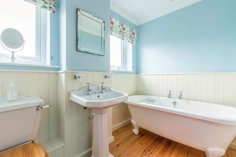 Family bathroom - fitted with a WC, a wash hand basin and a freestanding double ended bath. There are two rear facing obscure double glazed window, panelled walls and a central heating radiator