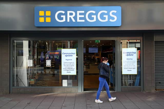 An woman wearing a face mask as a precautionary measure against covid-19, walks past a Greggs (Photo by GEOFF CADDICK / AFP) (Photo by GEOFF CADDICK/AFP via Getty Images)