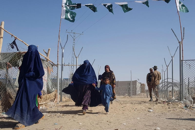 Pakistani soldiers stand guard as stranded Afghan nationals return to Afghanistan at the Pakistan-Afghanistan border crossing point in Chaman