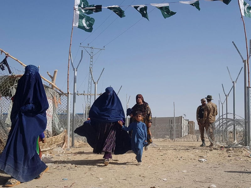 Pakistani soldiers stand guard as stranded Afghan nationals return to Afghanistan at the Pakistan-Afghanistan border crossing point in Chaman