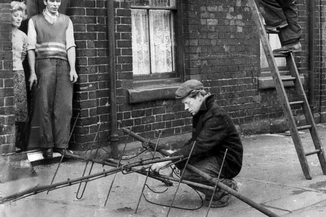 Mr and Mrs Edward Thiel of Amberley Street, Attercliffe, watch as workmen repair their tv aerial after the 1962 hurricane